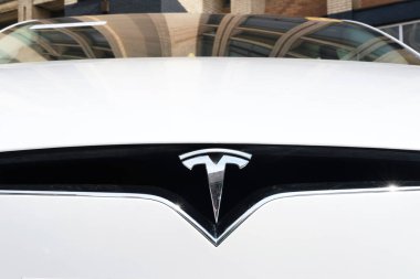 Minsk, Belarus - 10 Nisan 2025: Beyaz elektrikli bir arabada bulunan Tesla amblemi, sürdürülebilir taşımacılıktaki gelişmeleri ve çağdaş tasarımı vurguluyor