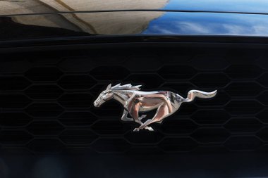 Minsk, Belarus - 10 Nisan 2025: Ford Mustang logosu şık siyah bir arabanın ızgarasında parıldıyor, klasik tasarımı ve otomotiv mirasını vurguluyor.