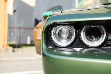 Minsk, Belarus - 10 Nisan 2025: Renkli arka plan elementlerine sahip parlak tasarım ve işçiliği vurgulayan yeşil kaslı araba farlarının yakın görüntüsü