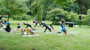 Minsk, Belarus - 06 Mayıs 2025: Canlı bir park ortamında grup yoga dersi, doğa ve yeşillikle çevrili paspaslarda yer alan katılımcılar