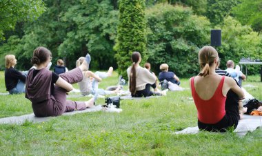 Minsk, Belarus - 08 Ağustos 2025: Çevresi yeşilliklerle çevrili, doğa sağlığı ve uygunluğunu destekleyen çeşitli gruplar minderlerle açık hava yoga seansına katıldı
