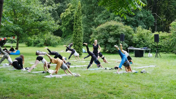 Minsk, Belarus - 06 Mayıs 2025: Canlı bir park ortamında grup yoga oturumu, çeşitli katılımcıların yeşilliklerle çevrili paspaslar üzerinde poz vermeleri