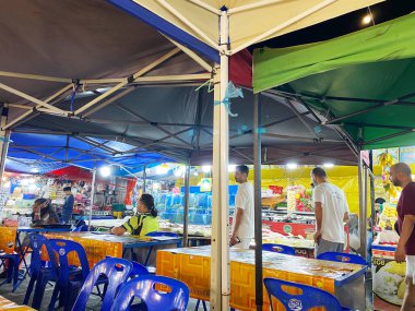 Phuket, Tayland - 27 Ekim 2025: Phuket 'te canlı çadırları, plastik oturma yerleri ve aydınlatılmış gıda tezgahları olan sokak kafesi canlı bir akşam atmosferi yaratıyor.
