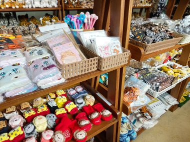 Phuket, Tayland - 27 Ekim 2025: Konforlu oyuncaklar, kırtasiyeler ve ahşap raflardaki aksesuarlar gibi kaplanlarla ilgili canlı ürünler