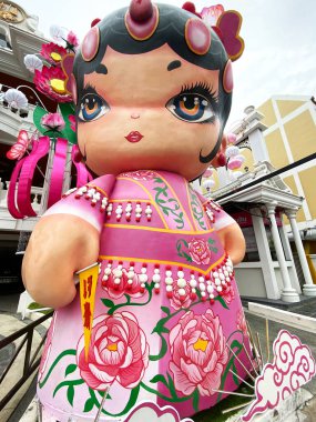 Phuket, Tayland - 28 Ekim 2025: Phuket 'in eski kasabasında yer alan, geleneksel pembe elbiseli, çiçeklerle süslenmiş büyük bir dekoratif figür.