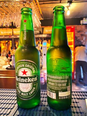 Phuket, Tayland - 29 Ekim 2025: Heineken bira şişeleri içki dolu bulanık arka plan rafları ile bir bar tezgahına yerleştirilmiş