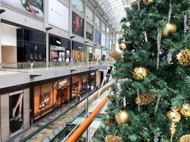Singapur, Singapur - Kasım 04, 2025: Altın madalyalı Noel ağacı canlı bir alışveriş merkezinde, neşeli alışveriş havasını yakalıyor.