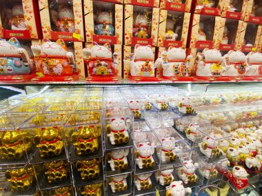 Singapur, Singapur - Kasım 04, 2025: Bir dükkandaki şanslı kedi heykelciklerinin canlı çeşitleri, benzersiz tasarımlar ve renkli ambalajlar