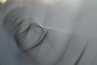 Kasıtlı Kamera Hareketi (ICM) kullanılarak uzun pozlu yaratıcı bir fotoğraf. Görüntü, modern tasarım, hız ve dijital geçiş duygusunu çağrıştıran serin tonlu ışık yayları ve hayalet geometrik ağ dokusuna sahiptir..