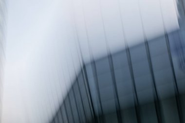 Dikey ışık yolları ve hareket bulanıklığı içeren soyut bir mimari kompozisyon. Görüntü, sıcak turuncu ve serin mavi tonlardan oluşan ritmik bir desen sergiliyor. Bu da günbatımında modern bir gökdelen ya da kentsel yapı olduğunu gösteriyor..