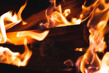 Görüntü, alevlerde yumuşak hareket bulanıklığı ve arka planda atmosferik gölgeler barındıran yoğun sıcaklığı ve çatırdayan ateşin sıcak parıltısını yakalar..