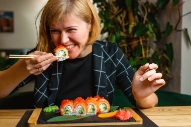 Kadın rahatlamış bir yemek anında suşi böreğini seve seve ısırır..