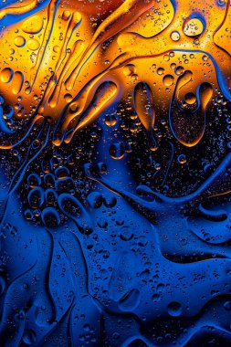 Rich blue liquid mixed with golden oil shapes, artistic macro background.