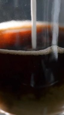 Bir bardak taze kahveye süt eklenir. Yakın plan. Dikey video.