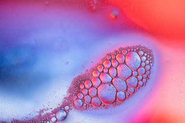 Küçük kabarcık kümelerinin sanatsal bileşimi canlı mavi ve pembe sıvı arka planda..