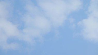 Yumuşak beyaz bulutların çerçevede yavaşça hareket ettiği açık mavi gökyüzünün video görüntüleri. Huzurlu doğal atmosfer, hava kavramları, özgürlük, dinginlik, yaz gökyüzü, doğa sahneleri ve soyut atmosferik görseller için uygundur..