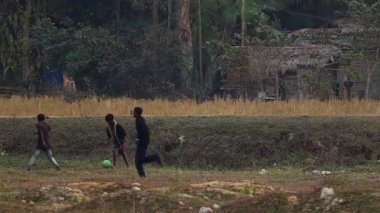 Ocak 2024, Assam, Hindistan. Bir grup çocuk ağaçlar ve tarım arazileriyle çevrili bir kırsal alanda futbol oynuyor. Sahne, Hindistan 'ın kuzeydoğusundaki bir köy ortamında çocukluk eğlencesi, toplum hayatı ve günlük anları yansıtıyor..