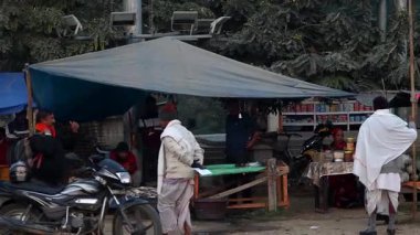 Dibrugarh, Assam, Hindistan 15 Ocak 2026: Kuzeydoğu Hindistan 'daki günlük ticaret ve köy yaşamını yansıtan motosiklet ve mallarla yol kenarındaki bir pazarda durup alışveriş yapan insanlar.