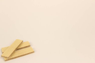 Hafif arka planda istiflenmiş çıtır gofret çubukları. Tatlı tatlı çayla ya da kahveyle mükemmel olur. Fotokopi alanı, tatlı konsepti, şekerleme ürünleri, hafif atıştırmalık ve fırın ürünleri ile basit kompozisyon.