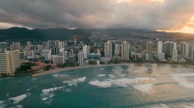 Hawaii 'de binalar kıyı boyunca sıralanmıştır. Güneş batarken dalgalar sahile vurur. Okyanus ve şehir ufkuna sıcak bir ışık yayar..