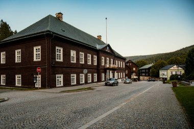 Ahşap kulübeleri, park edilmiş arabaları, boş mağazaları, yön işaretleri ve uzaklığı olan dağ kaldırımlı bir cadde.
