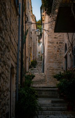 Yıpranmış kireçtaşı duvarları, saksı yeşili ve demir fenerler boyunca uzanan Taş Geçidi Merdiveni.,