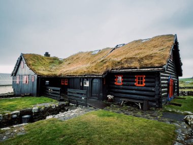 Kalın Çimen Çatılı ve Parlak Kırmızı Pencere Çerçeveli Siyah Kereste Kulübesi Geleneksel Kerestelerin Kapanışı