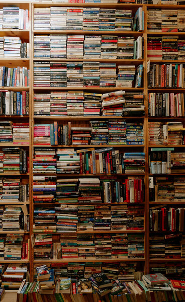 Tall Shelves Packed With Colorful Books Create Dense Reference Wall, FloorToCeiling Volumes And Varied
