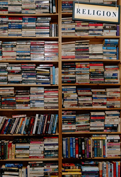 Religion Books Stacked In Wooden Shelves, Dense Rows Of Theology And Spiritual Titles With Worn Spines,