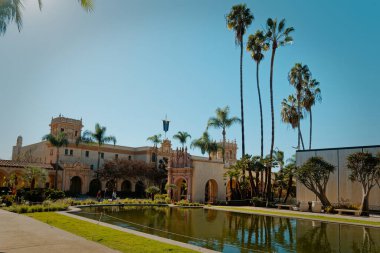 Güneşli İspanyol Uyanış Binası Palmiyeler ve Yansıyan Havuz, Manikürlü Çimler, Süslü Kemerler ve Mavi Gökyüzü,