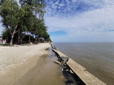 Hasarlı deniz kenarları plajı gölgeleyerek kıyı aşınmasını ve doğal alanların eğlence amaçlı kullanımını vurguluyor..