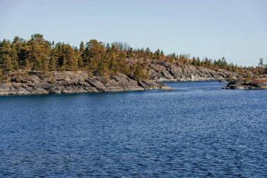 Gündüz vakti güneş ışığı altında mavi derin göl manzarası, gökyüzünde bulutlar Ladoga skerries Karelia