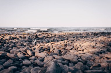 Okyanus göletinin çakıl taşı plajı, bulutlu bir günde deniz manzarası.