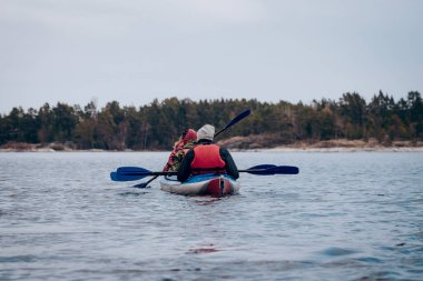 Saimaa, Finlandiya, 10 Mayıs 2019, bulutlu bir günde sakin gölde uzanan kano, orman ağaçları ve su arka planı