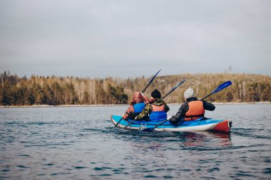 Saimaa, Finlandiya, 10 Mayıs 2019, bulutlu bir günde sakin gölde uzanan kano, orman ağaçları ve su arka planı