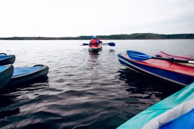Saimaa, Finlandiya, 10 Mayıs 2019, bulutlu bir günde sakin gölde uzanan kano, orman ağaçları ve su arka planı