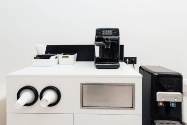 Kahve otomatı mesai saatleri için ofis masasında sıcak içecek yapıyor.