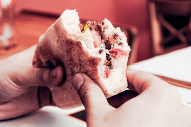 Fast food restoranına gelen ziyaretçilerin elinde sebzeli ve etli panini sandviçi.