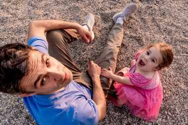Aile babası ve kızı yaz tatilinde sahilde yürüyor.