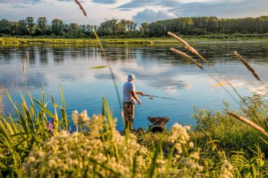 Saimaa, Finlandiya, 1 Temmuz 2020, Nehir kıyısında balıkçı oltasıyla balık tutan balıkçı.