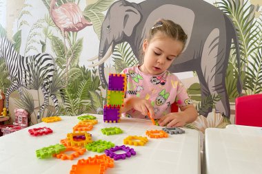 Bar, Karadağ, 7 Temmuz 2025, inşaat blokları ve yapı kulesi montajı ile oynayan tatlı kız çocuğu