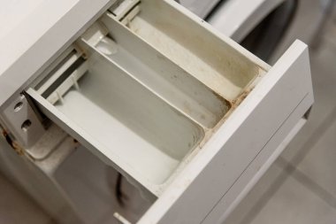 Kirli tepsi çekmecesi eski çamaşır deterjanı ve kireçtaşı kaplı katı su yüzünden.