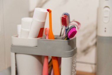 Diş fırçaları ve diş macunları banyoda raftaki plastik kutuda.