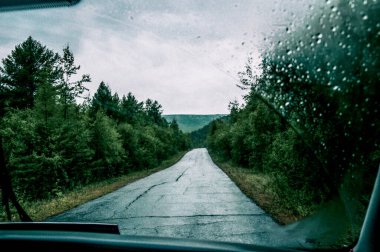 Bulutlu bir sonbahar gününde otoyolun asfalt bozuk banliyö yolundaki otomobilin ön camından bak.