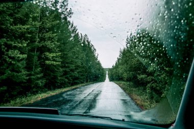 Bulutlu bir sonbahar gününde otoyolun asfalt bozuk banliyö yolundaki otomobilin ön camından bak.
