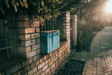 Mavi posta kutuları güneşli bir sonbahar gününde tuğla çit kenar mahalle sokağında asılı.