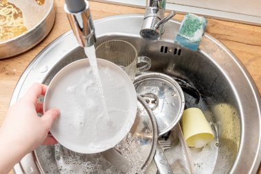 Kadın elleri bulaşıkları yıkar, ev hanımları ev işlerini yapar ve evi temizler.