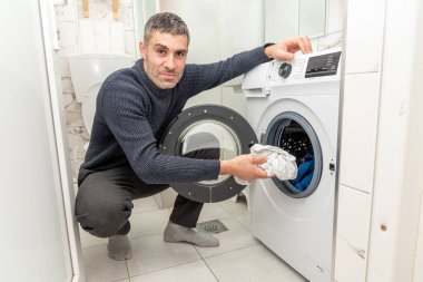 Kirli çamaşırları çamaşır makinesine koyan adam varil, yaşam tarzı ev işleri
