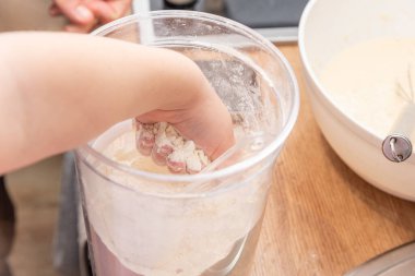 Küçük çocuk un alıp ev yapımı krep hamuruyla birlikte kaseye koyuyor.
