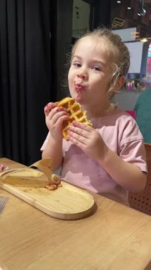 Kahvaltıda waffle yiyen tatlı kız, yüzüne meyve reçeli bulaşmış çocuk.